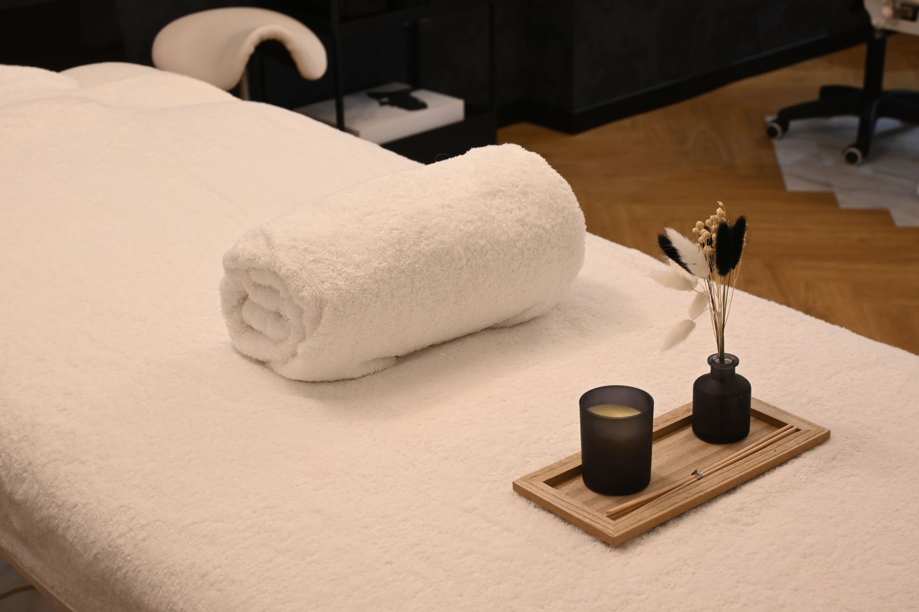 Treatment table in a calm med-spa room, set with a rolled white towel and a small wooden tray